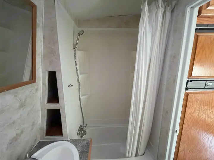 This RV rental features a compact bathroom with a shower/tub, sink, mirror, and storage shelves, perfect for your travel adventures.. Eclipse Recreational Vehicles Attitude 2007