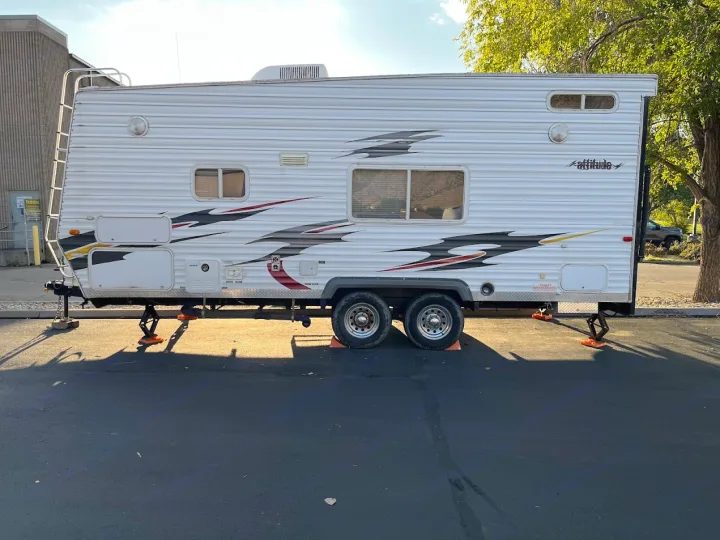 White "Attitude" travel trailer (RV rental) with leveling jacks parked on a sunny asphalt lot.. Eclipse Recreational Vehicles Attitude 2007