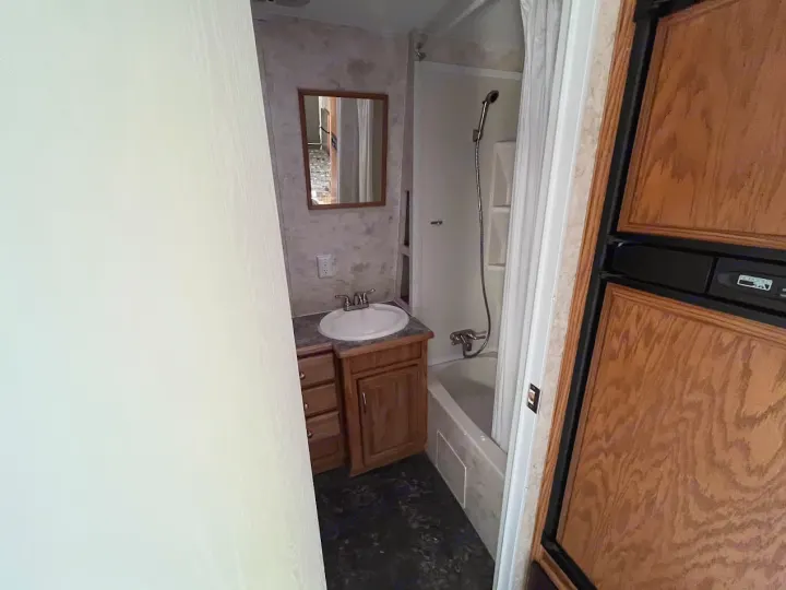 Small RV rental bathroom featuring a sink, mirror, vanity, shower/bathtub, and a portion of a refrigerator.. Eclipse Recreational Vehicles Attitude 2007