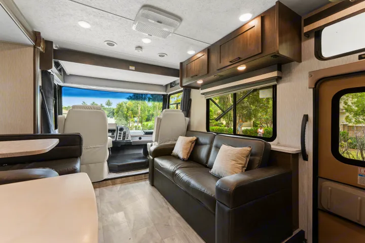 Spacious rv rental interior with cockpit, sofa, and dinette, perfect for road trips. See the comfortable living space!. Coachmen Pursuit 2024