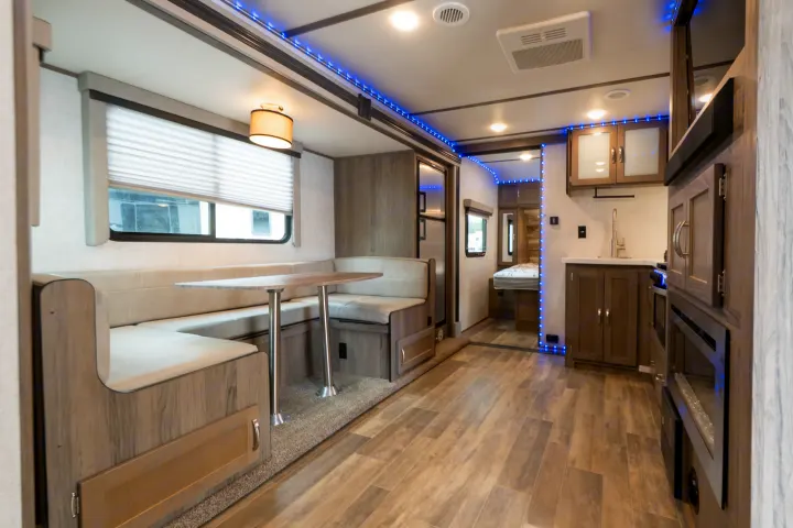 Sleek RV rental interior featuring a bright dinette, efficient kitchen, and inviting bedroom, all lit by ambient blue LEDs.. Gulf Stream Envision 2021