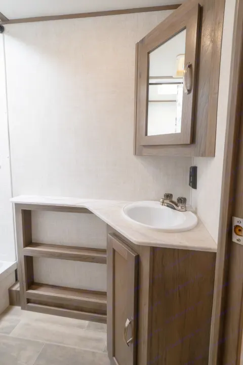 Modern RV rental bathroom vanity with a white sink, mirrored cabinet, and open shelving for convenience.. Gulf Stream Envision 2021