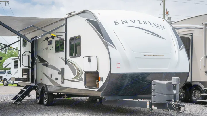 Explore this white Envision travel trailer RV rental, featuring an extended awning and steps, perfect for your next camping adventure.. Gulf Stream Envision 2021