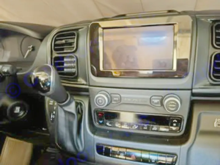 Interior of an RV rental: Dashboard features a central touchscreen, gear shifter, and climate controls in this modern van cockpit.. Custom Promaster 2500 2025