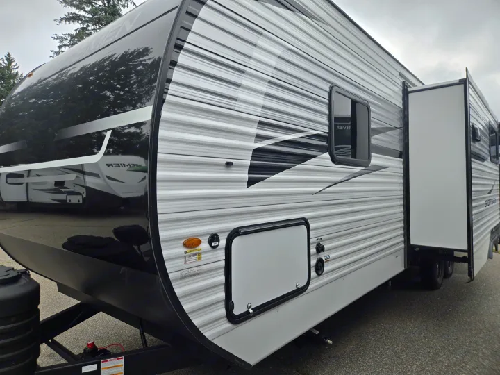 This rv rental travel trailer features a glossy black front, striped grey side with graphics, a partially extended slide-out, and utility access.. KZ Sportsmen 291BHK 2027
