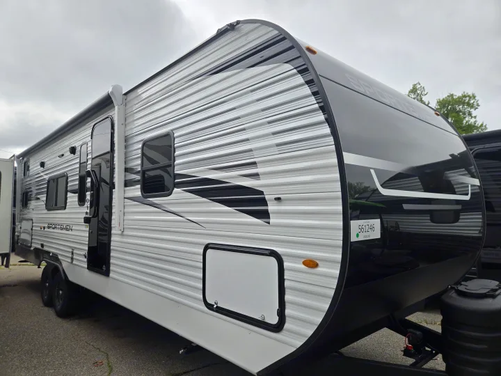 This white and black Sportsmen travel trailer, ideal for rv rental, features an awning and multiple windows for your next adventure.. KZ Sportsmen 291BHK 2027