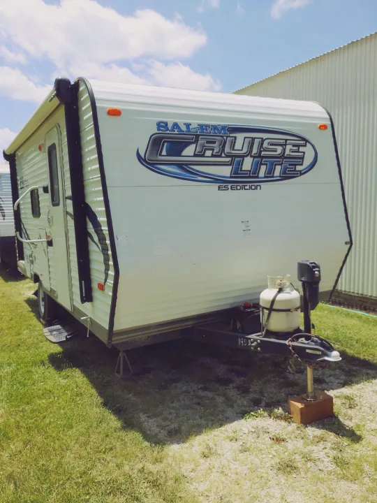 White Salem Cruise Lite RV rental travel trailer parked outdoors, ready for adventure. Features a propane tank.. Forest River Salem Cruise Lite 2014
