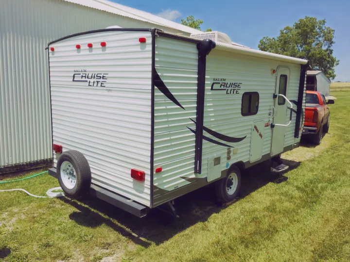 White Salem Cruise Lite rv rental travel trailer with a spare tire on the back, parked on green grass outdoors.. Forest River Salem Cruise Lite 2014