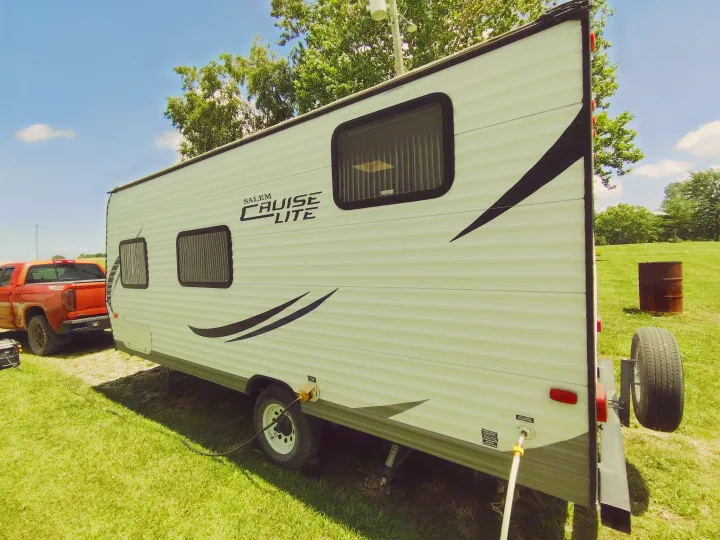 White Salem Cruise Lite rv rental travel trailer parked on grass with a truck. Connected to utilities, ready for an outdoor camping adventure.. Forest River Salem Cruise Lite 2014