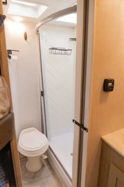 RV rental: Bright, clean bathroom featuring a toilet, curved shower with herringbone walls, and skylights.. Forest River Salem Cruise Lite 2023
