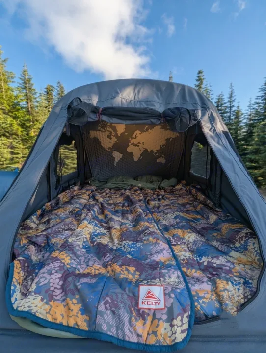 Rooftop tent on an rv rental, featuring a vibrant Kelty sleeping bag & world map interior. Perfect for forest camping!. Jeep Wrangler 2012