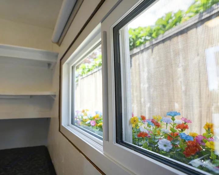 RV rental interior: A screened window offers colorful flower views. Shelves line the compact, cozy space.. Micro-Lite Micro Camper 1987