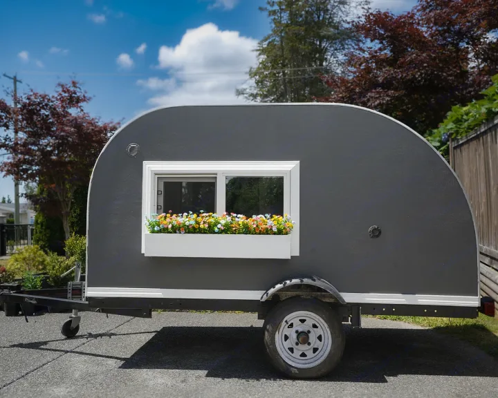 Unique gray teardrop RV rental with a decorative flower window box, parked outdoors on a sunny day.. Micro-Lite Micro Camper 1987