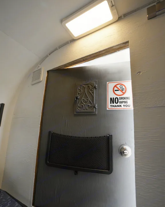 Compact RV rental interior featuring a "No Smoking Vaping" door, bright light, and ventilation.. Micro-Lite Micro Camper 1987