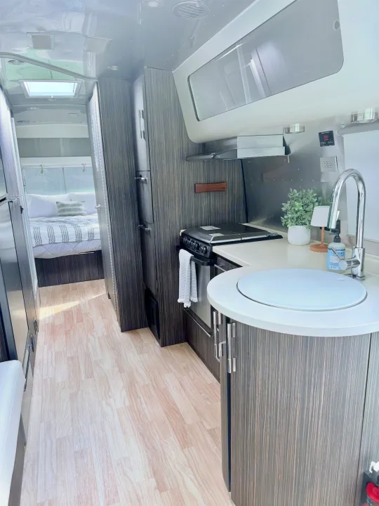RV rental interior: A modern kitchen with a round sink and a cozy bedroom in the back. Ideal for a comfortable road trip.. Airstream International 2018