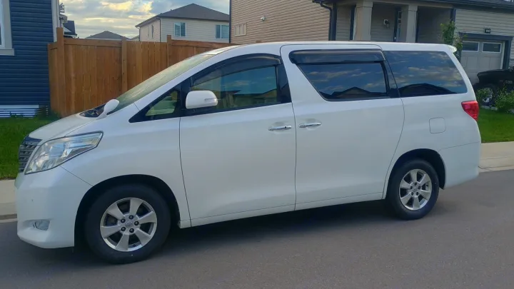 Large white minivan, potentially for an rv rental alternative, parked on a residential street under a cloudy sky.. Toyota HIACE CAMPERVAN 2010