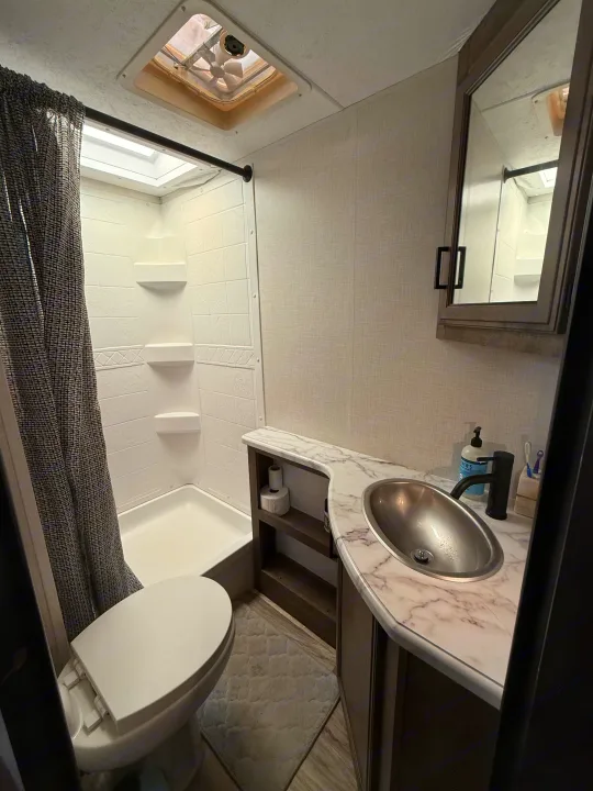 Clean and functional RV bathroom with shower, toilet, sink vanity, and mirror, perfect for your next rv rental adventure.. Venture Venture Trailer 2023
