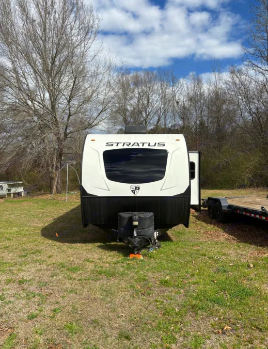 Get ready for an RV rental outdoor adventure! This white Stratos travel trailer sits in a grassy field under a cloudy sky.. Venture Venture Trailer 2023