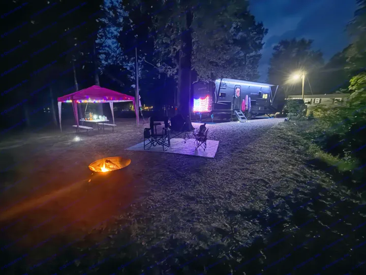 RV rental campsite at night with a lit RV, vibrant canopy, and warm campfire for a cozy outdoor experience.. Venture Venture Trailer 2023