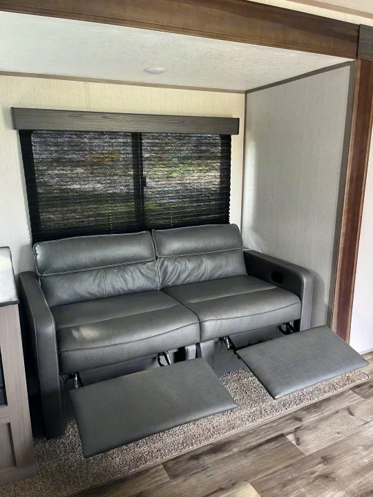 A comfortable, modern grey recliner sofa with extended footrests in an RV rental, offering a cozy living space.. Dutchmen Coleman Lantern LT 2022