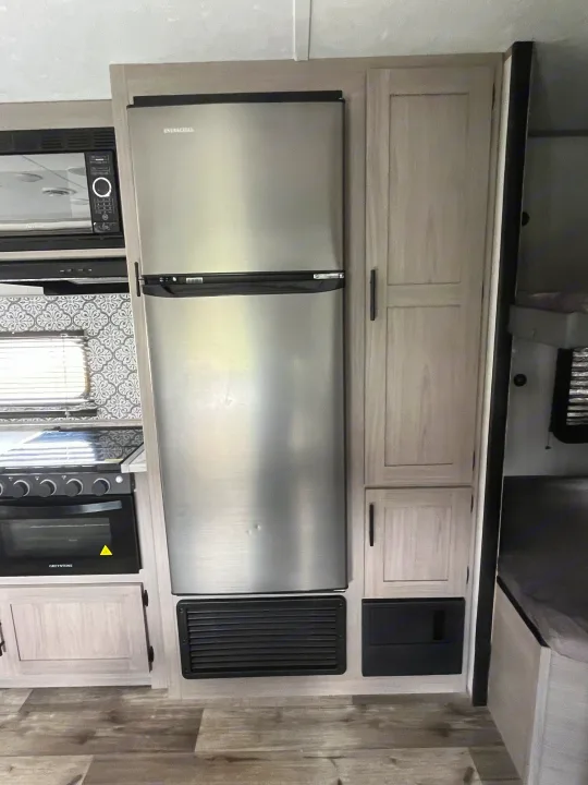 RV rental kitchen: stainless steel EverChill fridge, microwave, Greystone stove, light wood cabinets, patterned backsplash.. Dutchmen Coleman Lantern LT 2022