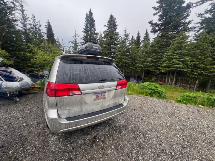 Silver Toyota Sienna minivan with cargo box & boat, parked on gravel in a wooded area. Ready for RV rental adventure.. Toyota Toyota Sienna XLE 2005