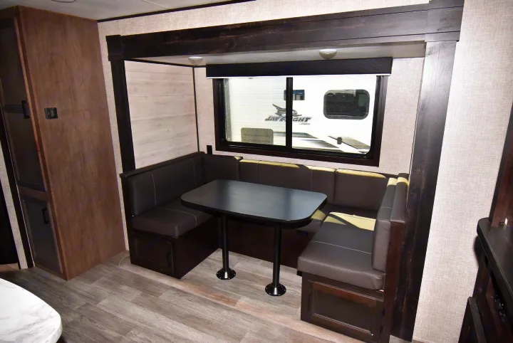 Modern RV dinette with U-shaped booth seating and table, featuring a large window. Perfect for your rv rental getaway.. Jayco Jay Flight 2023