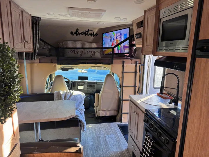 Cozy RV rental interior: overhead bunk, TV, dinette, and full kitchen, perfect for adventure.. Forest River Sunseeker LE 2018