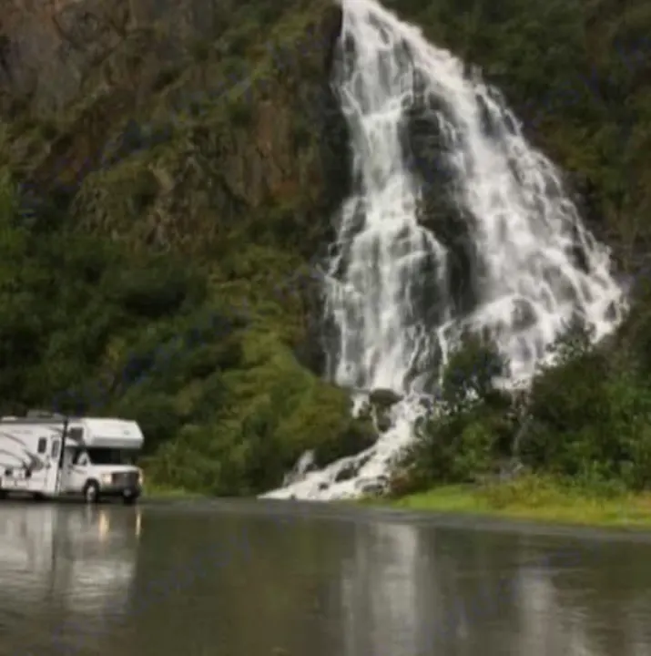 Visually impaired: An RV rental is parked on a wet road next to a majestic waterfall cascading down a lush hillside.. Forest River Sunseeker LE 2018