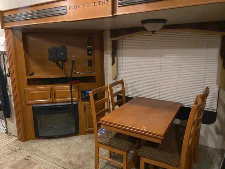 RV rental interior featuring a wooden dining table, chairs, built-in entertainment center, and an electric fireplace.. Keystone RV Montana High Country 2013