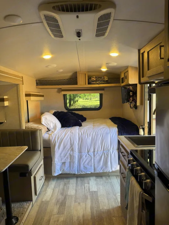 This RV rental offers a compact, cozy interior with a bed, dinette, kitchen, and scenic window view.. Forest River Rockwood Geo Pro 2022