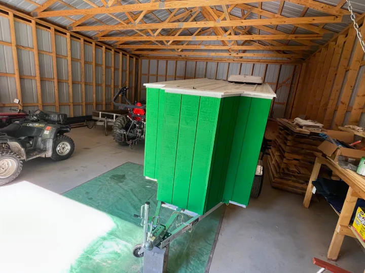 Bright green custom mobile shelter on a trailer with a roof vent, stored in a barn. This unit could serve as a unique rv rental.. Custom Custom 2025
