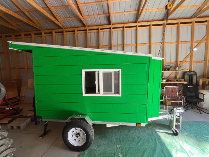 Custom-built green micro-camper trailer, possibly for rv rental, parked indoors. Features a window & white trim.. Custom Custom 2025