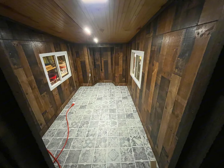 Spacious RV rental interior featuring rustic wood paneling, a bright patterned floor, and windows, ready for your next adventure.. Custom Custom 2025