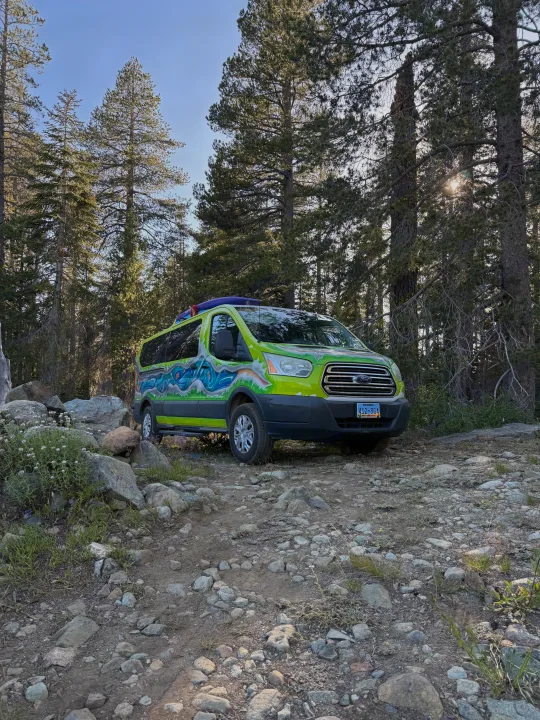 Artistic rv rental van with kayak on top, on a rocky forest path under sunny pine trees. Ready for adventure!. Ford Transit 2017