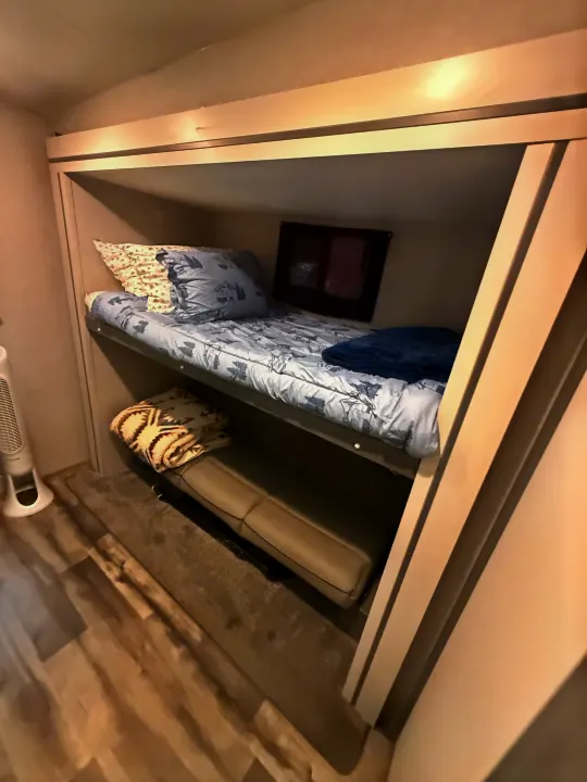 RV rental: Cozy bunk bed setup. Upper bed has blue bedding, lower is a sofa. Includes a fan & small window.. Crossroads RV Volante 2022