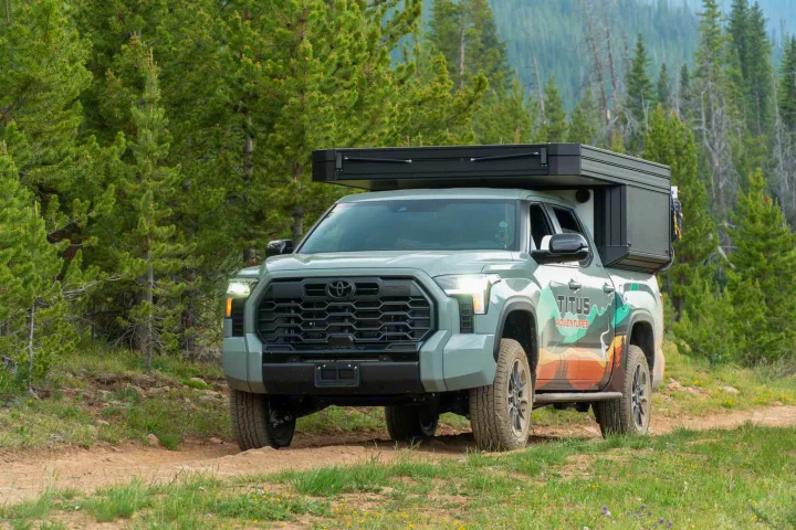 Green Toyota Tundra RV rental with a camper unit on a forest trail. Perfect for rugged off-road adventure.. Toyota Tundra 2026