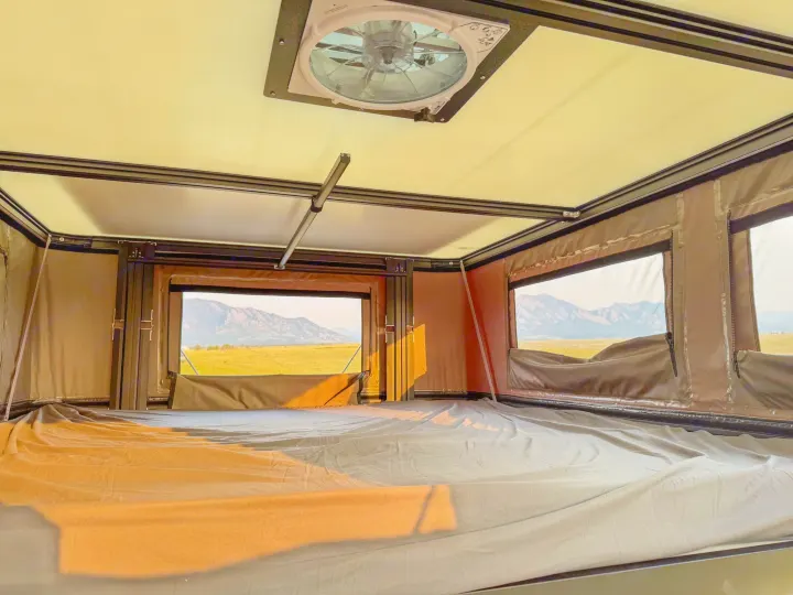 Inside this RV rental's rooftop tent: a comfortable bed, ceiling fan, and stunning mountain views await your camping adventure.. Toyota Tundra 2026