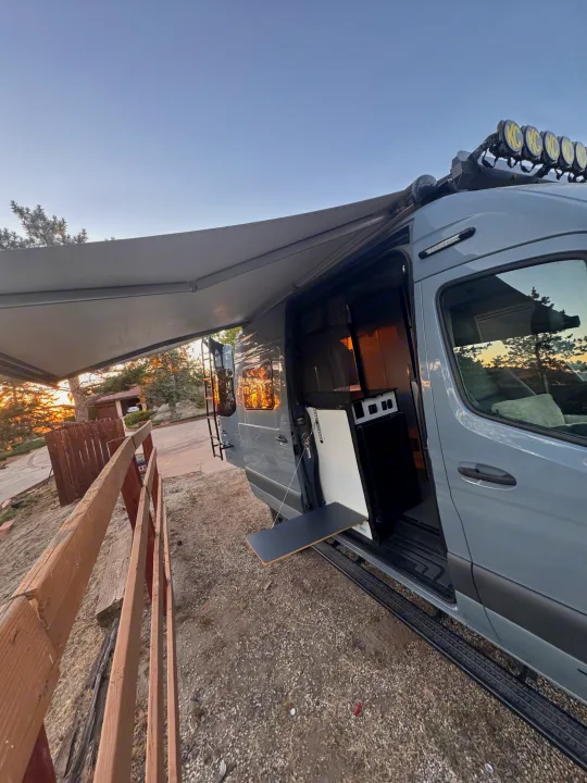 Experience adventure with this RV rental! A custom camper van featuring an extended awning, exterior table, and roof lights, ideal for outdoor enjoyment.. Winnebago Revel 2022
