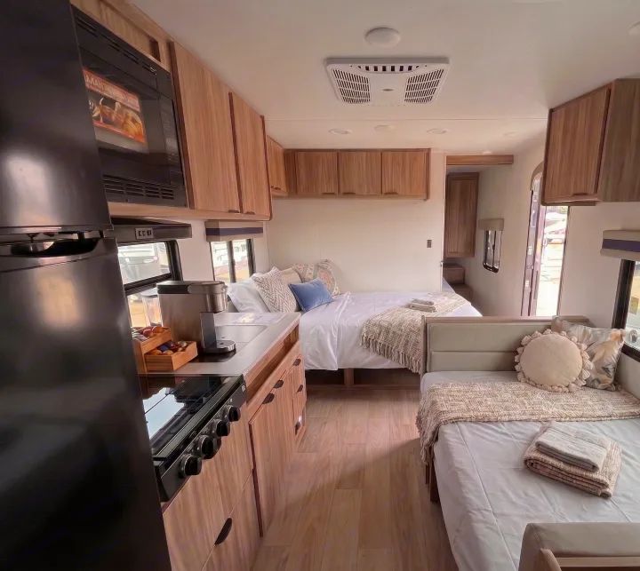 Step inside this modern **RV rental**: a compact kitchen with appliances, a comfy main bed, and an additional sleeping nook await your adventure.. Winnebago Access 2025