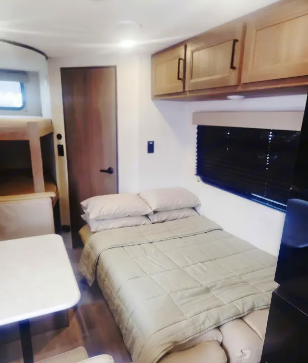 Cozy RV rental interior with bunk beds, a comfy bed, dining area, and cabinets. Perfect for your next adventure!. Grand Design Transcend Xplor 2025