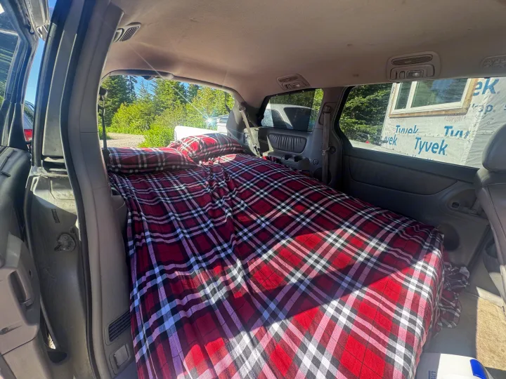This minivan features a comfortable red plaid bed, transforming it into a budget-friendly rv rental for road trips.. Toyota Toyota Sienna XLE 2005
