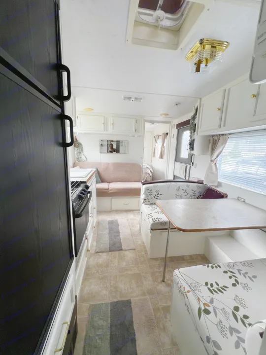 Step inside this bright RV rental, featuring a kitchen, dining booth with floral cushions, and a cozy sofa area.. Kustom Koach Westwind 2004