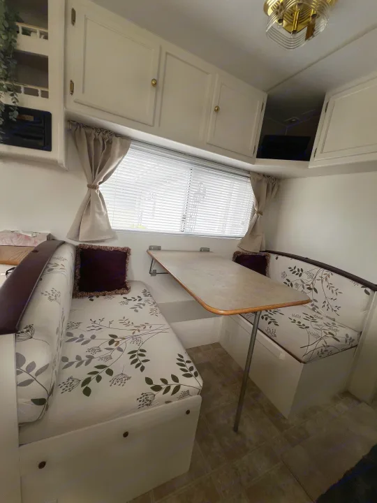 Inside this inviting rv rental, find a comfortable dinette with botanical print cushions, window blinds, and practical overhead storage.. Kustom Koach Westwind 2004