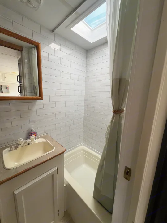 RV rental bathroom with modern tiled walls, sink, mirror, and shower/tub combo. Natural light from skylight.. Kustom Koach Westwind 2004