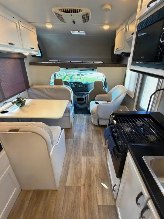 Spacious rv rental interior showing a full kitchen, comfortable dinette, and front cockpit view, perfect for road trips.. Thor Four Winds 2019