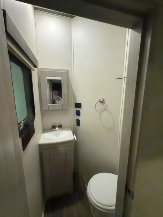 This RV rental's compact bathroom features a vanity with sink, mirror, and toilet. Modern, clean interior for your trip.. Keystone Fuzion 2021