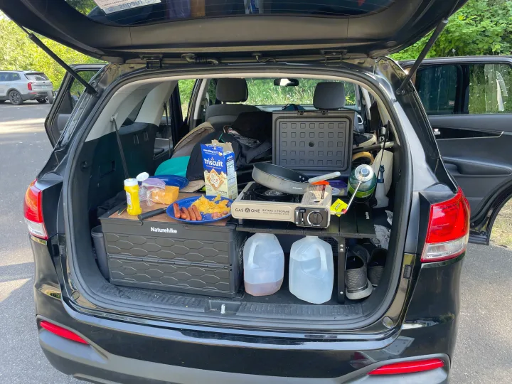 This RV rental alternative shows a car camping kitchen in an SUV trunk, with a portable stove, food, and Naturehike gear ready for a road trip.. KIA Sorento 4X4 2017