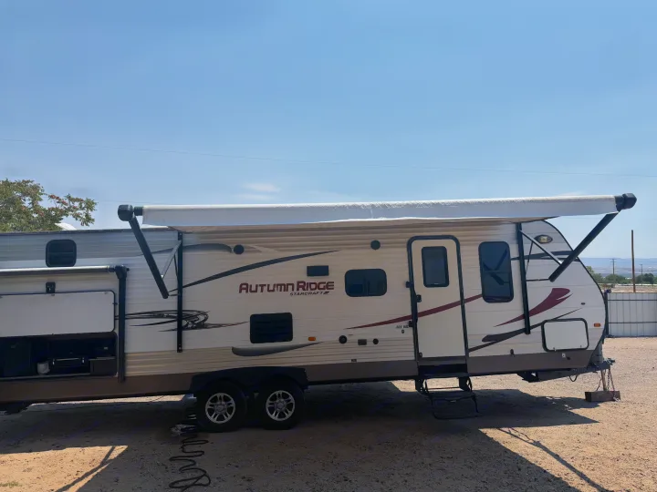 Autumn Ridge rv rental: A cream and brown travel trailer with an extended awning and outdoor storage, parked under a clear sky.. Starcraft Autumn Ridge 2015