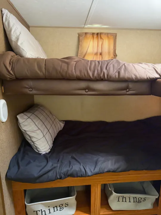Inside an RV rental: cozy upper and lower bunk beds, complete with bedding, pillows, and "Things" storage bins.. Starcraft Autumn Ridge 2015